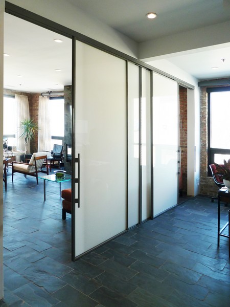 large living and dining rooms divided by sliding white painted glass doors with large pull handles and metal accents