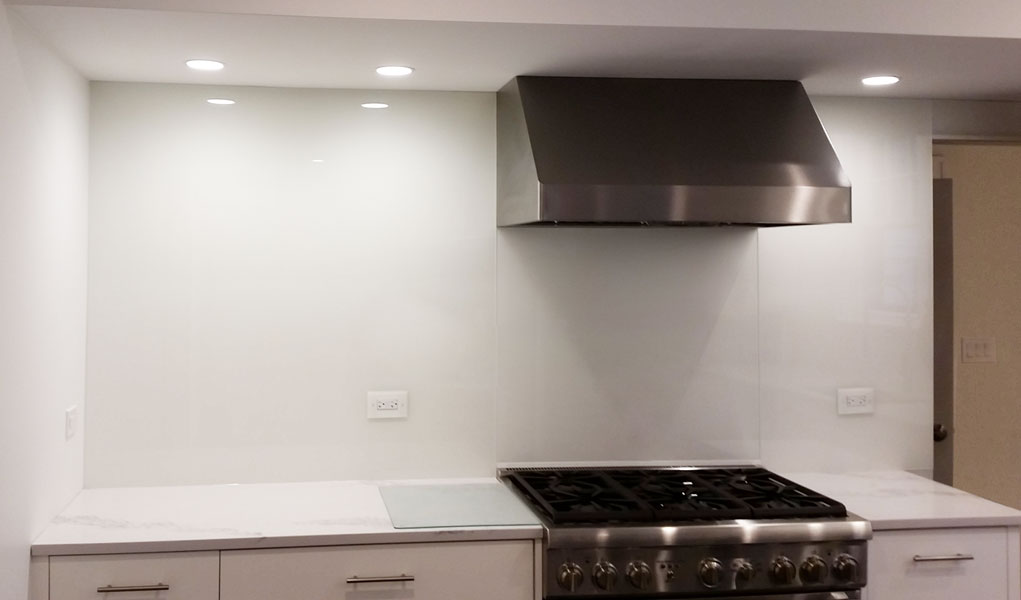 all white kitchen with white cabinets and custom seamless white glass backsplash to the ceiling