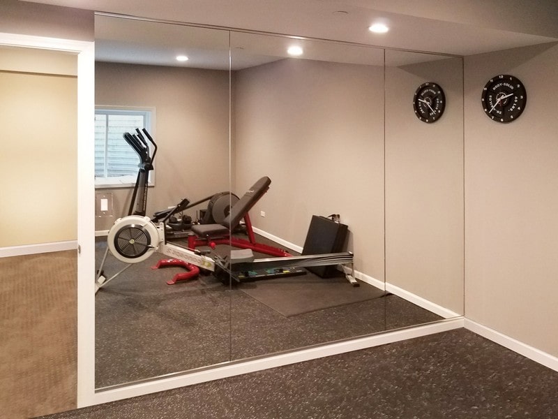 a home gym set up with a custom mirror extending from the doorway, flush to the corner where that wall meets another