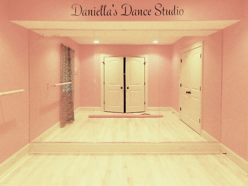 a home dance studio with a bar on the left wall and the back wall is entirely filled with a large custom mirror