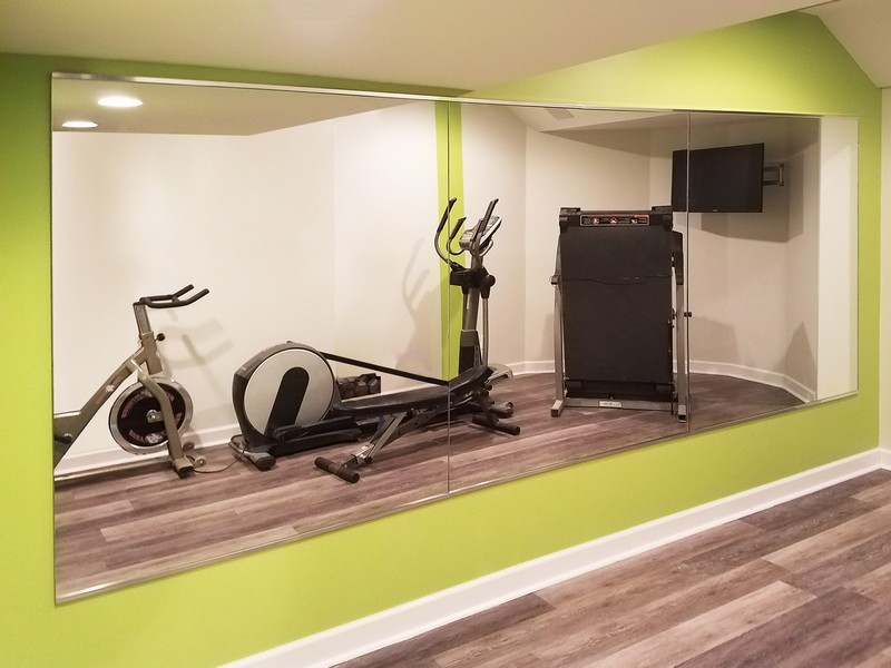 one very large, long mirror reflecting an exercise bike in a modern home gym