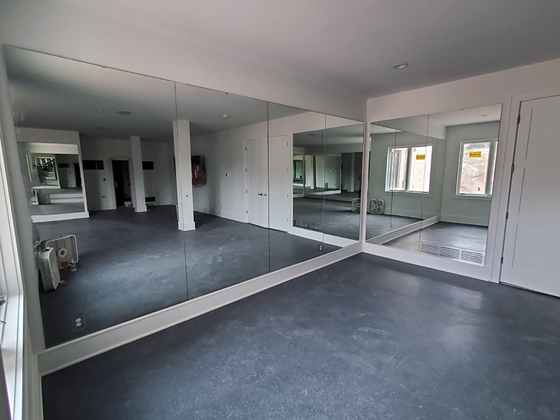 four large frameless mirrors filling the back wall of a home gym set up inside a garage