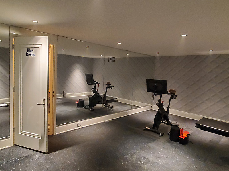four large frameless mirrors filling the back wall of a home gym set up inside a garage