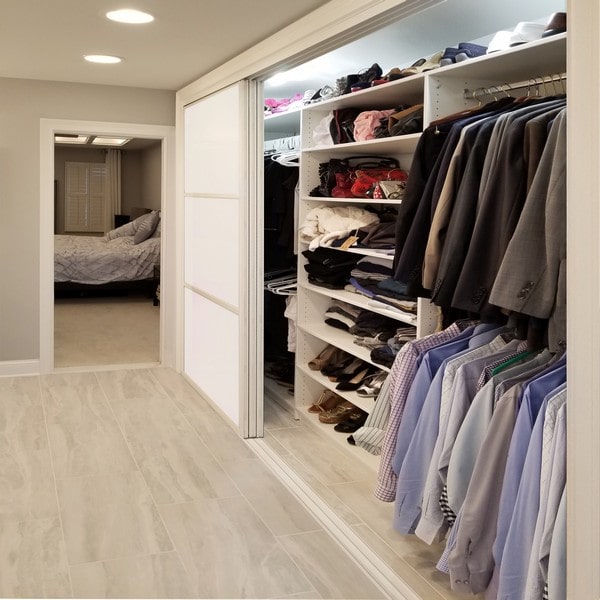 three section grid design white painted glass bypass sliding closet doors with two panels open to show hanging and folded clothes
